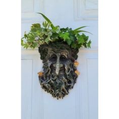 a door with a planter on it and a face made out of leaves in the center