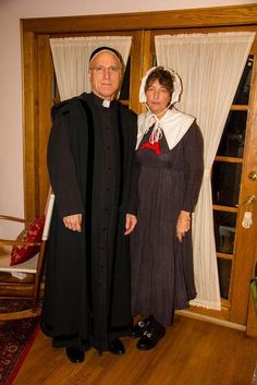 an older man and woman dressed in old fashion clothes standing next to each other on a wooden floor