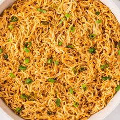 a bowl filled with noodles and topped with green onions