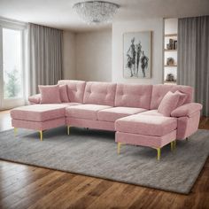 a pink sectional couch sitting on top of a wooden floor next to a rug in front of a window