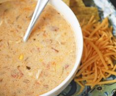 a white bowl filled with soup next to cheese and crackers on a blue plate