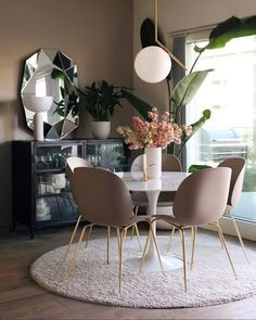 a dining room table and chairs with plants in the background