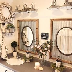 a bathroom sink with two mirrors on the wall and flowers in vases next to it