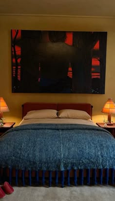 a bedroom with a large painting hanging above the bed and two lamps on either side of the bed