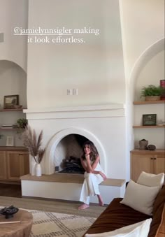 a woman is sitting in front of a fireplace