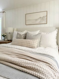 a bed with white sheets and pillows in a bedroom