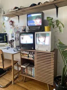 two televisions sitting on top of a wooden cabinet next to a desk and chair