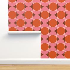 an orange and pink wallpaper with circles on it in front of a white wall