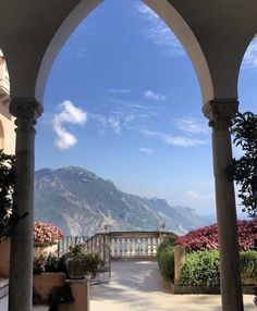 an outdoor area with arches and flowers in the foreground, mountains in the background