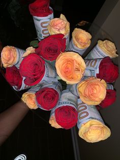 a bunch of flowers that are on top of a glass table in front of a person's hand