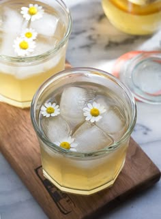 two glasses filled with ice and some daisies