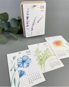 four calendars with flowers on them next to a plant