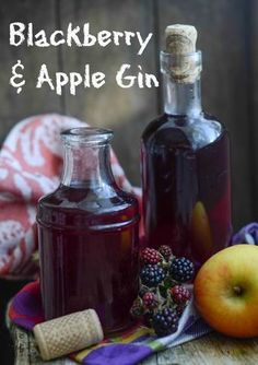 two bottles of blackberry and apple cider sitting on a table next to an apple