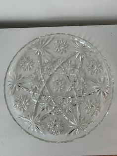 a clear glass plate sitting on top of a white tablecloth covered counter next to a wall