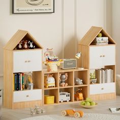 two wooden toy houses sitting next to each other on top of a white table in front of a window