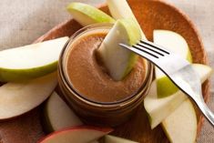 an apple slice sticking out of a jar filled with caramel and apple slices on a plate