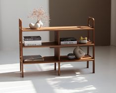 a wooden shelf with books and vases on it