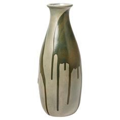 a white and green vase with brown drips on the bottom, against a white background