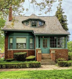 a small brick house with green trim and windows