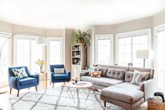 a living room with couches, chairs and a rug in front of two windows