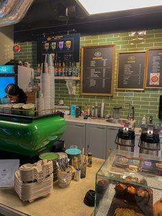 there is a green car on the counter in this coffee shop that has many cups and trays