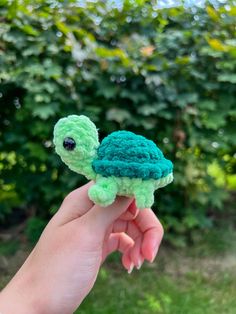 a hand is holding a small stuffed turtle