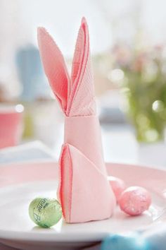 a pink bunny napkin sitting on top of a white plate next to a candy bar