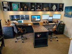 an office with two desks and three monitors on the wall above them is shown