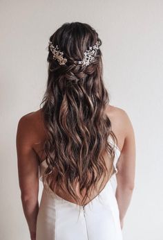 the back of a woman's head wearing a white dress with flowers in her hair