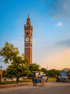 a horse drawn carriage in front of a tall tower with a clock on it's side