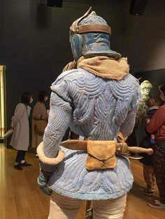 a man dressed in armor standing on top of a wooden floor next to other people