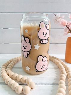 a jar filled with liquid sitting on top of a wooden bead necklace next to a vase