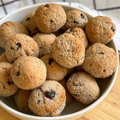 a white bowl filled with muffins on top of a wooden table