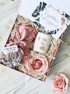 an open gift box with pink flowers and cards