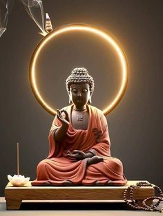 a buddha statue sitting on top of a wooden table next to a candle and incense