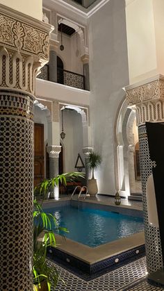 an indoor swimming pool in the middle of a building with columns and arches around it