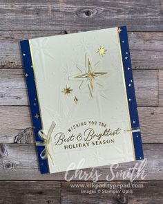 a white and blue christmas card sitting on top of a wooden table