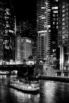 a black and white photo of a boat on the water in front of tall buildings