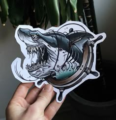 someone holding up a sticker with a shark on it