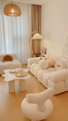 a living room filled with white couches and chairs next to a table in front of a window