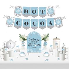 a table topped with cups and teapots covered in snowflakes next to a banner that says hot cocoa