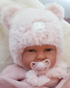 a baby doll with a pacifier in it's mouth wearing a bear hat