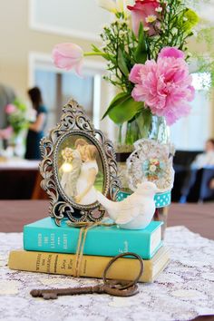 a table topped with two books and a vase filled with flowers on top of it