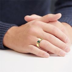 a woman's hand with a gold ring on top of her left hand and a green stone in the middle