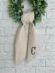 a wreath with the letter c hanging on a brick wall