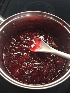 a ladle full of cranberry sauce sitting on top of a stove