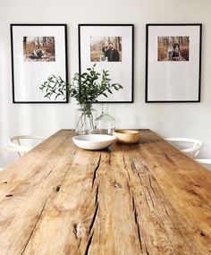 a wooden table with white chairs and pictures on the wall