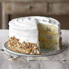 a cake with white frosting and chopped walnuts on top is sitting on a plate