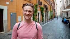 a young man standing in the middle of an alleyway with buildings on both sides