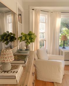 a living room filled with furniture next to a window covered in white curtained drapes